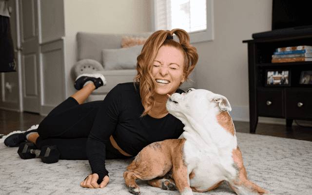 Kristie with her bulldog, Arnold, trying to lick her face.